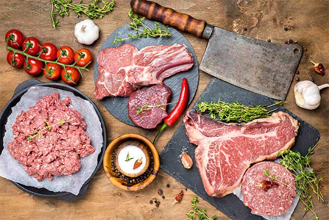 Various cuts of meat on a wooden table.